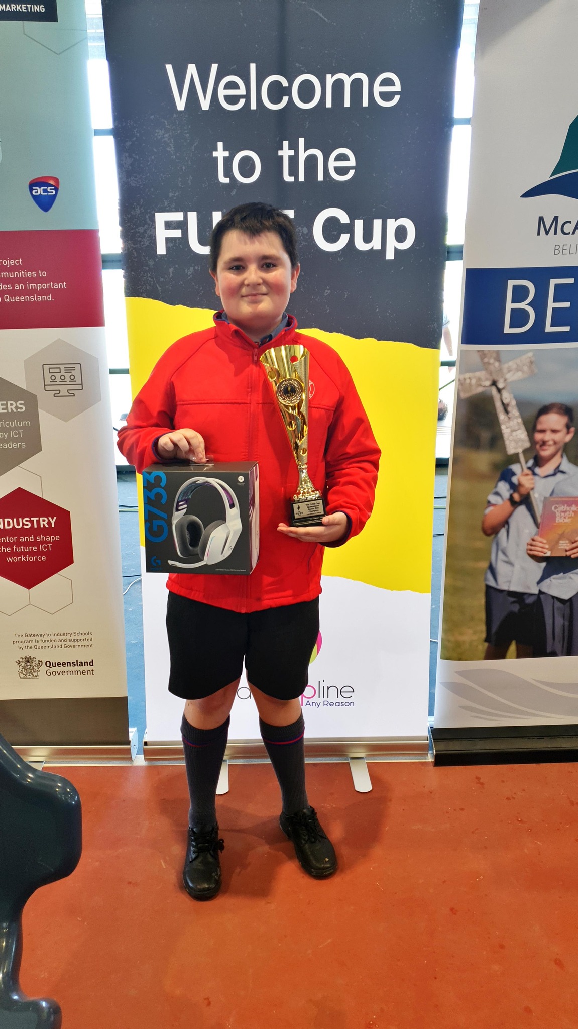 Student holding a trophy and prize at a school technology competition representing achievement recognition and success in ICT learning