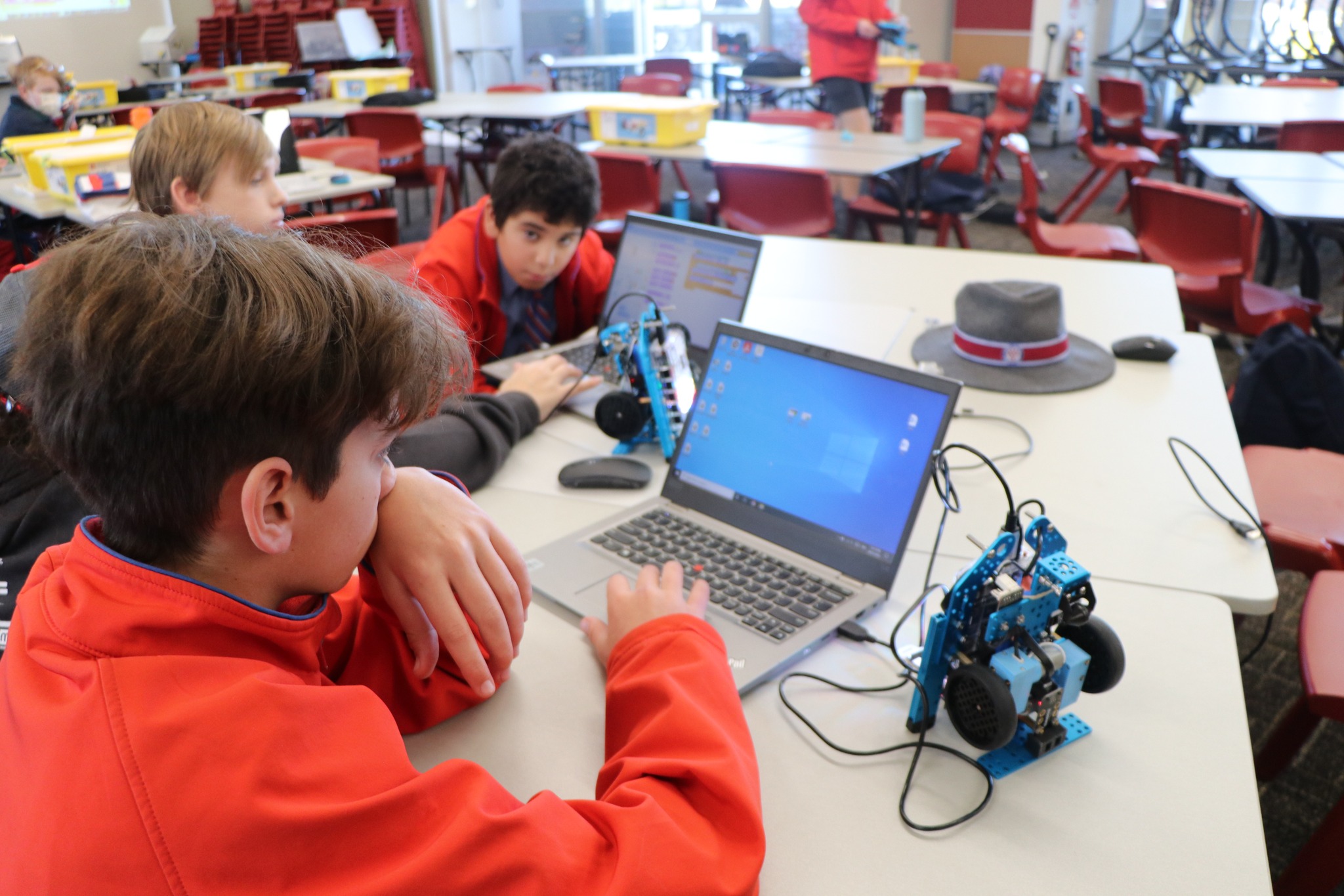 Students collaborating with laptops and robotics equipment in a classroom setting supporting coding skills problem solving and STEM learning
