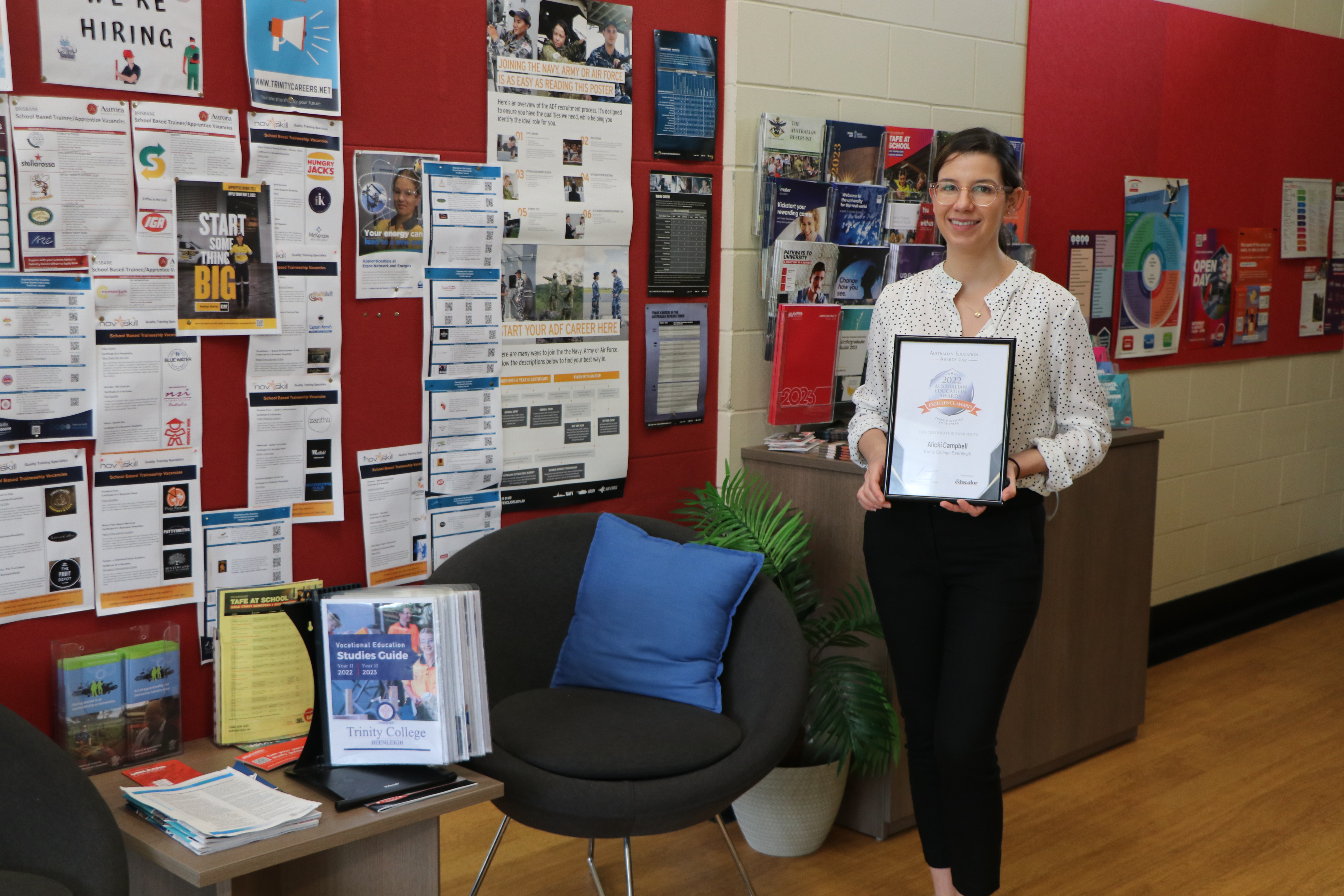 Staff member holding an award in a careers and pathways space highlighting achievement student support services and future planning opportunities within the school