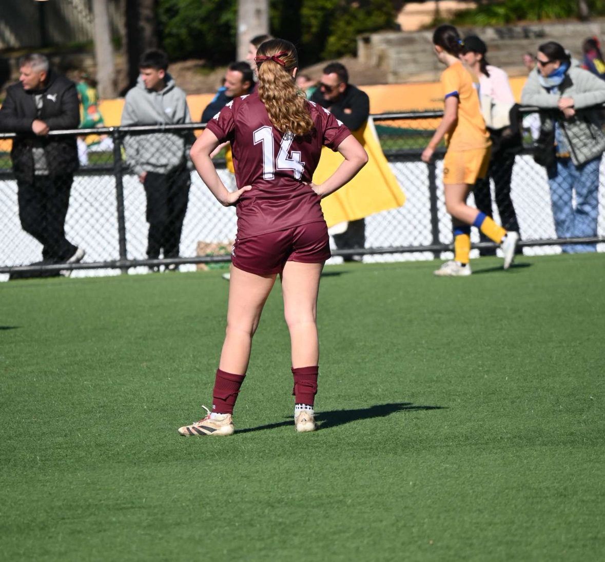 Student in sports uniform standing on a field during a match highlighting active participation and focus in school sport