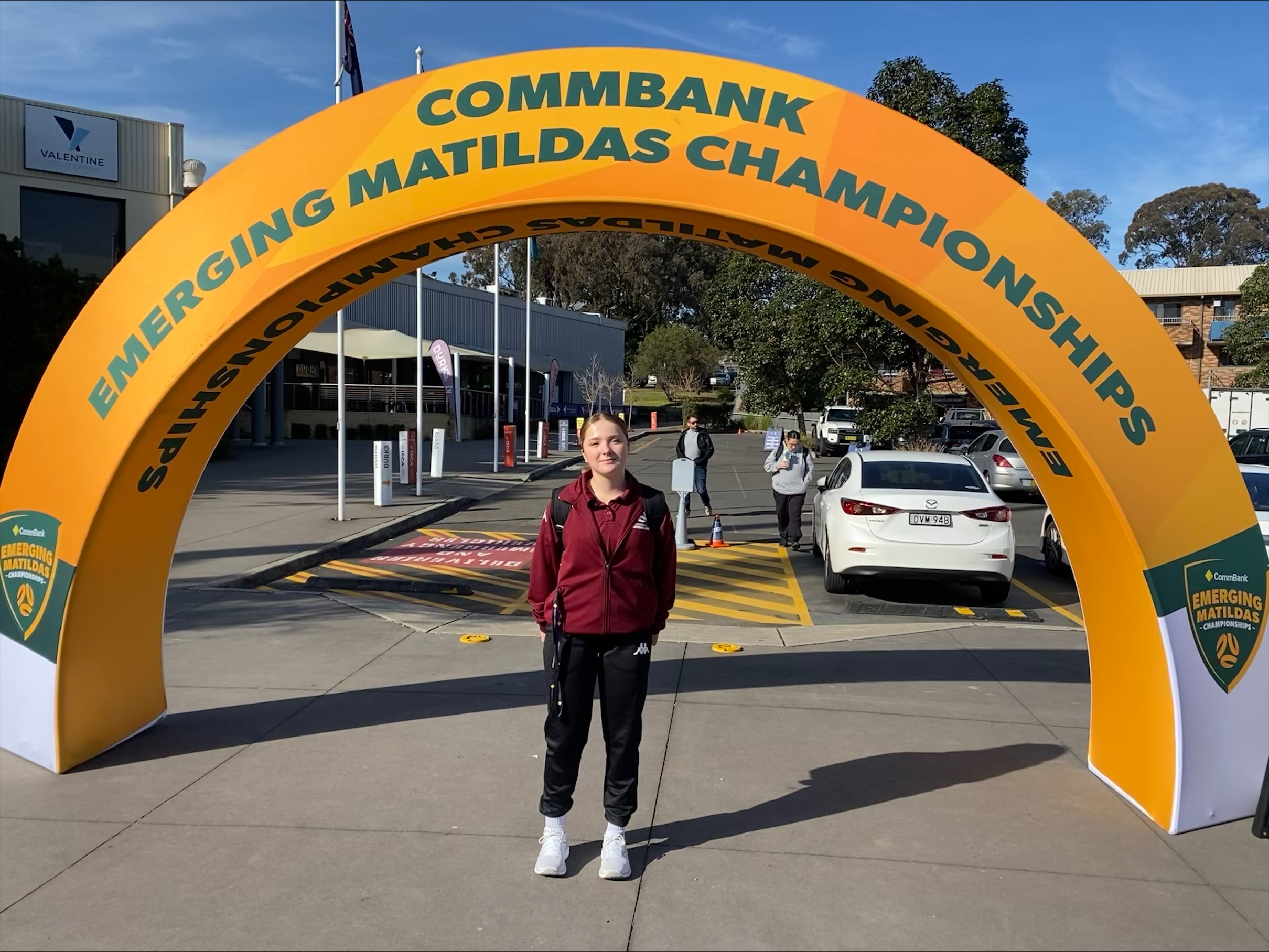 Student standing under Emerging Matildas Championships arch representing participation in a national sporting event and student achievement